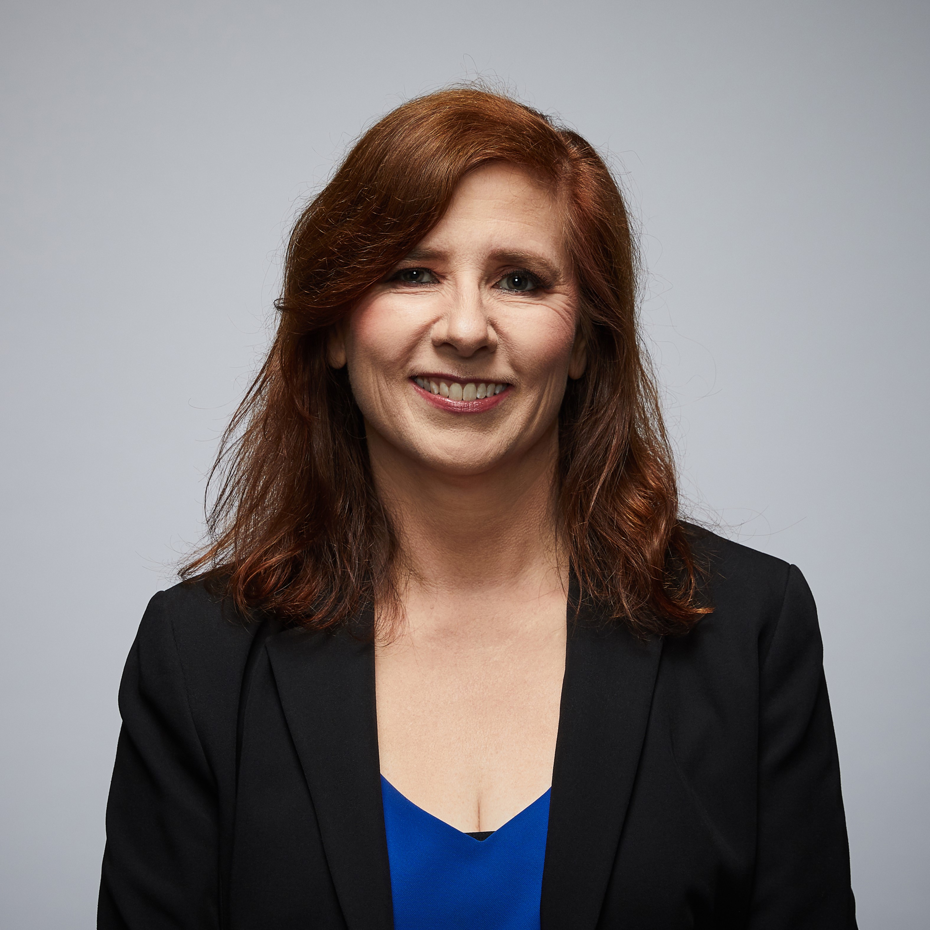 Annette's story Image of police spouse looking at camera wearing a dark blue jacket or blazer. Light skin and auburn hair